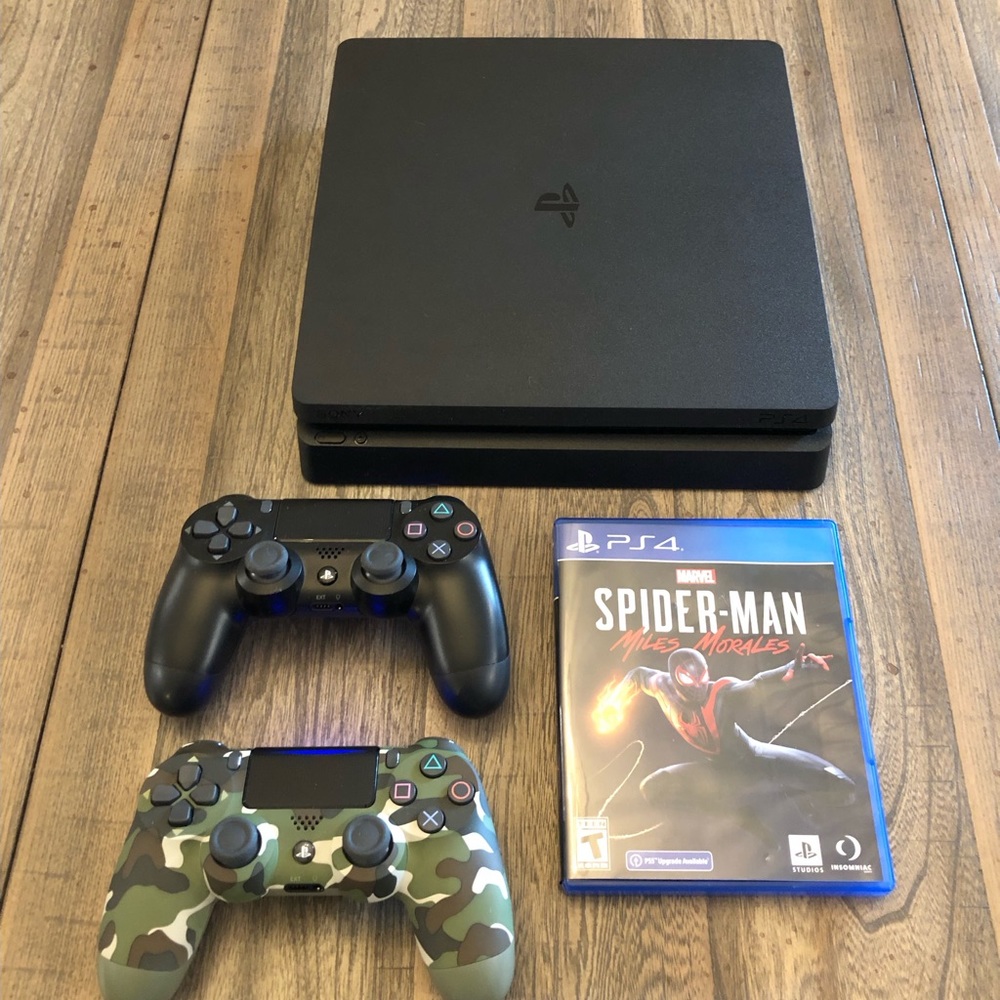 PlayStation 4 with two wireless controllers and Spider-Man game.